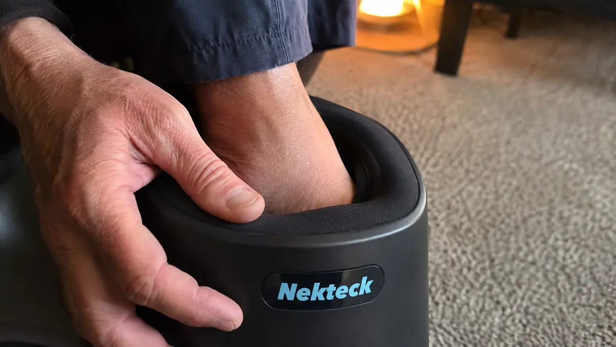 Close-up of a foot pulled slightly out of the foot massager cavity, showing how snug the fixed-size opening fits against the ankle