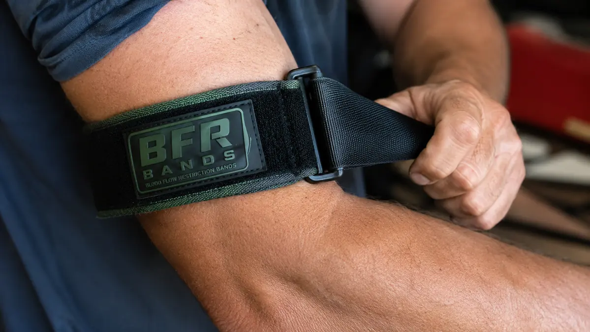 Close-up of hands adjusting the quick-release buckle on a BFR band around a forearm