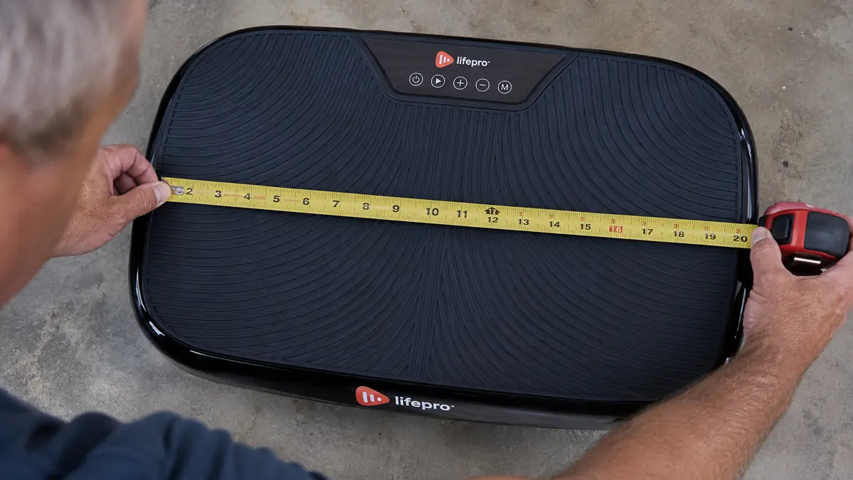 Close-up of a tape measure laid across the floor space the vibration plate and stepping clearance actually occupy